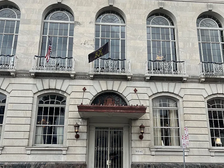 Stately street-facing entry with arched windows, ornate ironwork balconies, and a covered front doorway.