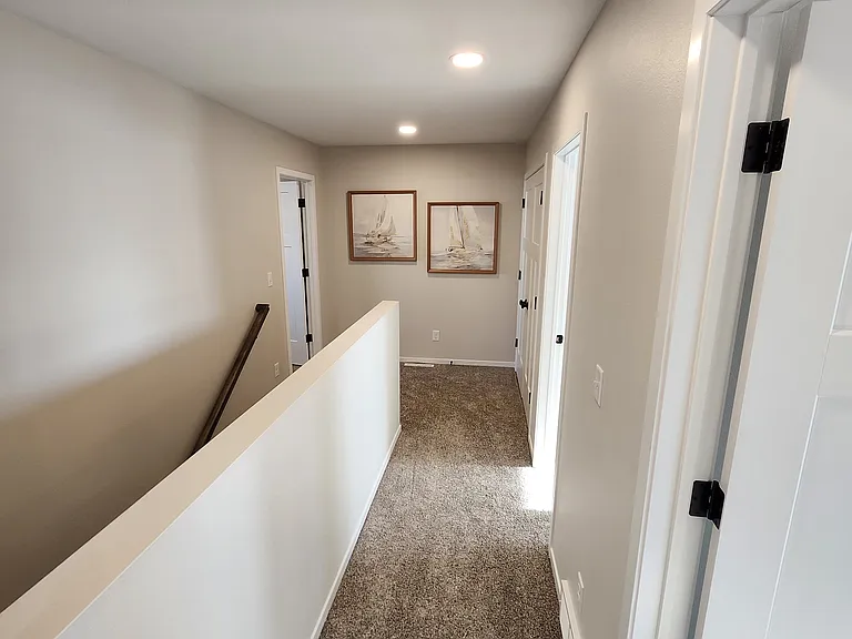 Hallway from upstairs bath looking toward bedrooms one, two and laundry (on right) & Primary (left). (Pictures are of another unit with similar finishes and features.)