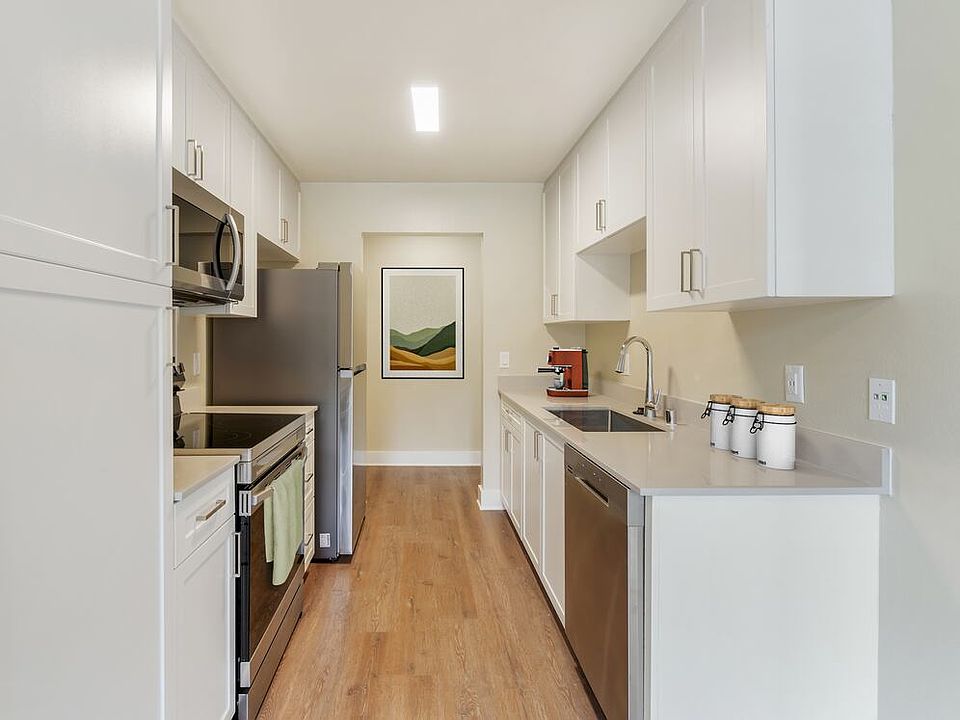 Renovated Package I kitchen with beige granite countertops, white cabinetry, stainless steel appliances, and hard surface flooring