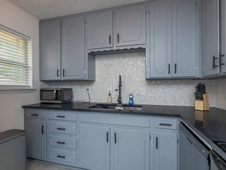 Fully stocked kitchen with a stainless steel range hood and cooking essentials