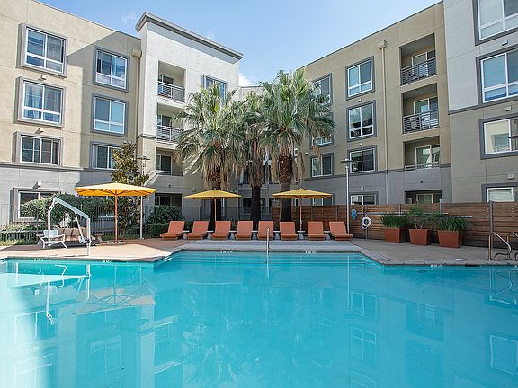 Resort-style pool at Aster Apartments in Dublin, CA, surrounded by lush landscaping and lounge seating.