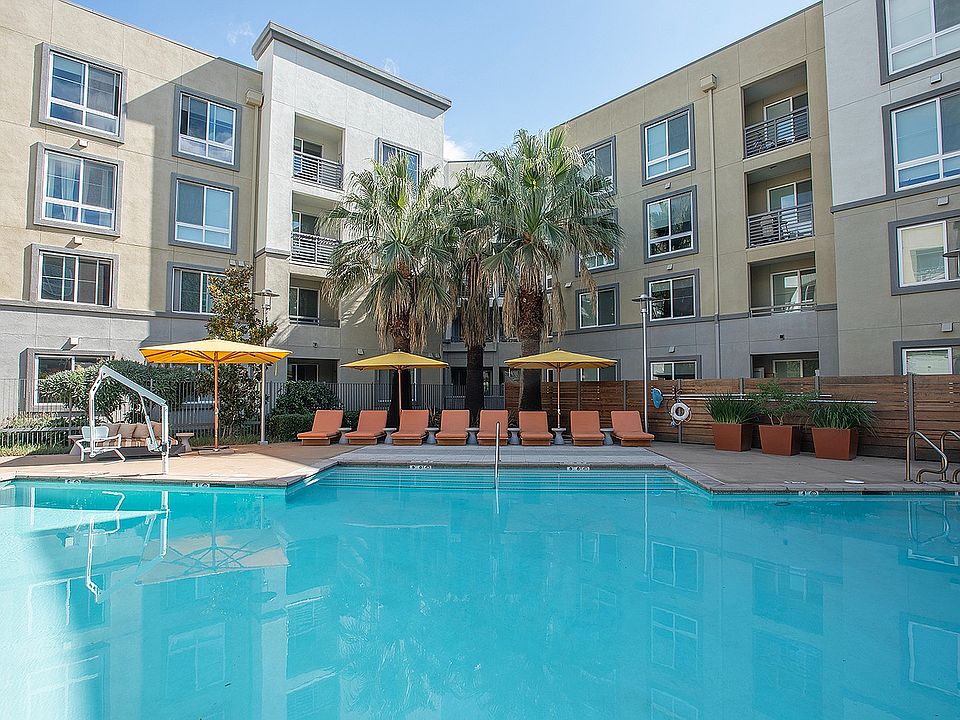 Resort-style pool at Aster Apartments in Dublin, CA, surrounded by lush landscaping and lounge seating.