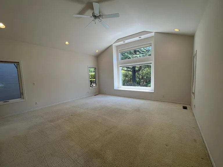 Large primary suite features high vaulted ceiling and a large picture window boasting the view of the lush garden.