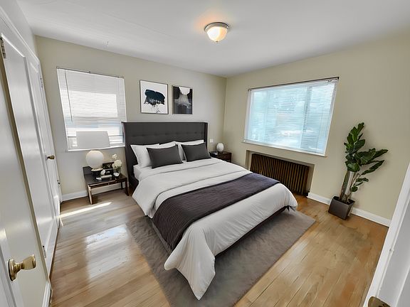 Elegant bedroom with modern decor, large windows, and warm hardwood flooring, creating a cozy and inviting ambiance. Elegant bedroom with modern decor, large windows, and warm hardwood flooring, creating a cozy and inviting ambiance.