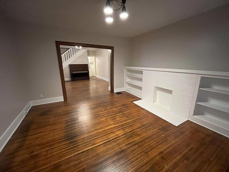 Large front living room with decorative fireplace and built in bookshelves.