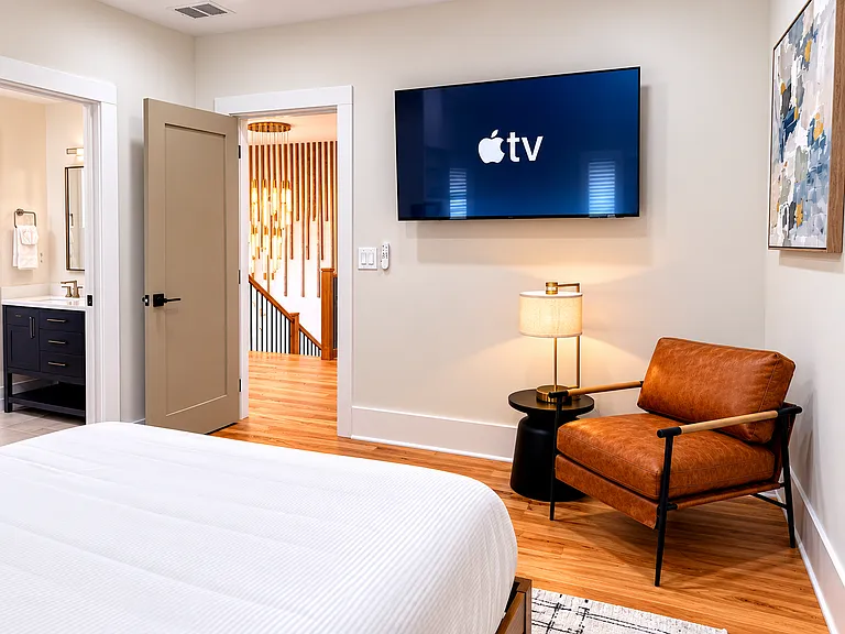Queen bedroom with calming blackout curtains, smart TV, bedside charging, plush bedding, spacious walk-in closet, seating, and a private, restful suite-style feel.