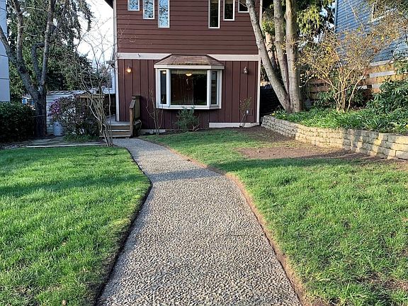 Front of house with landscaped yard. 2 bedrooms upstairs and living area facing front yard area.