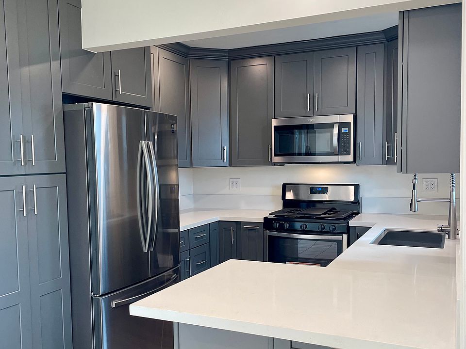 Kitchen with stainless steel refrigerator, gas stove, dishwasher and microwave. Also features custom cabinetry with ample storage space.