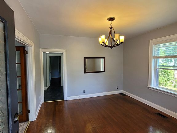 Living room from front door entry. Freshly painted and beautiful original wood floors and trim. Updated light fixtures.