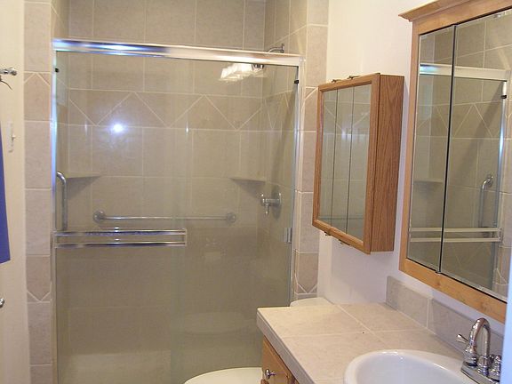 Tiled Bathroom with two medicine cabinets, tall shower head,