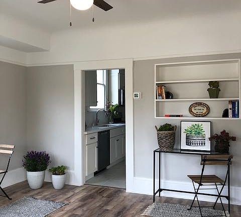 Enter into the living room with 9 foot coved ceilings, large windows, built in bookcase, wood laminate flooring, ceiling fan, decorator two tone paint.