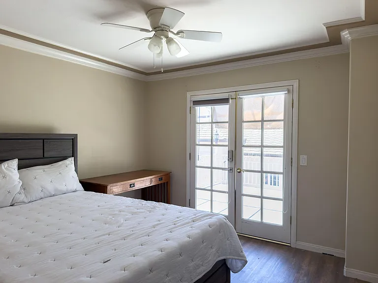 Bedroom with a ceiling fan, crown molding, and French doors that open to an outdoor balcony/patio area.