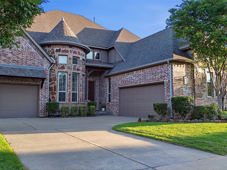 Brick and stone facade residence featuring a turret with bay windows, an arched entry, and a covered front porch