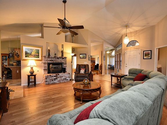 Spacious and gracious separate family room with brick fireplace, ceiling fan and beautiful wood flooring