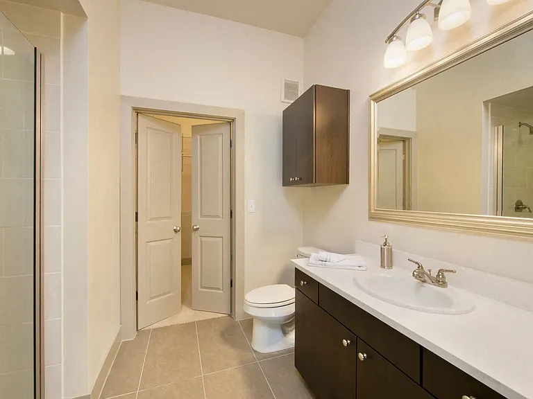 Luxury bathrooms with solid slab countertops, porcelain tile flooring, and custom framed mirrors