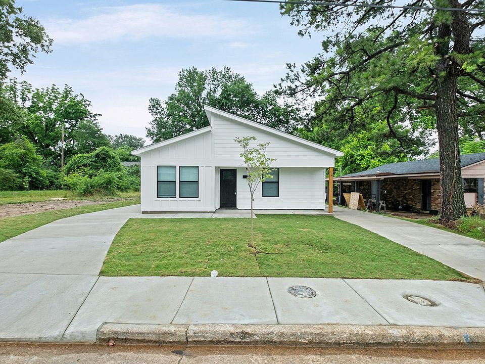 Single-story white home with a new concrete driveway and a clean exterior. The property is currently secured with boarded windows and doors