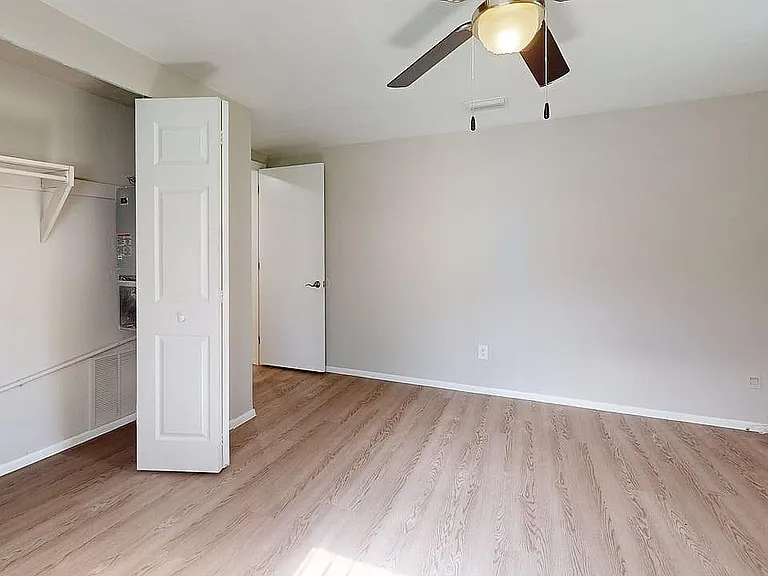 Bright and airy empty room with sleek wooden flooring, open closet space, and modern ceiling fan, ideal for customization and personal style.
