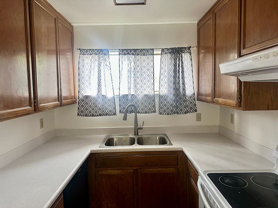 The kitchen is both functional and homey, featuring ample wooden cabinetry for storage and full-size appliances, including a refrigerator and electric stove. New Kitchen counters and kitchen sink.