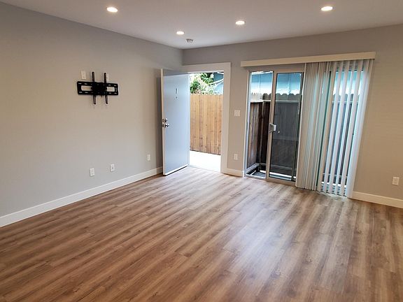 Brightly lit, large airy living room with luxury hard vinyl wood flooring with cork cushioning.