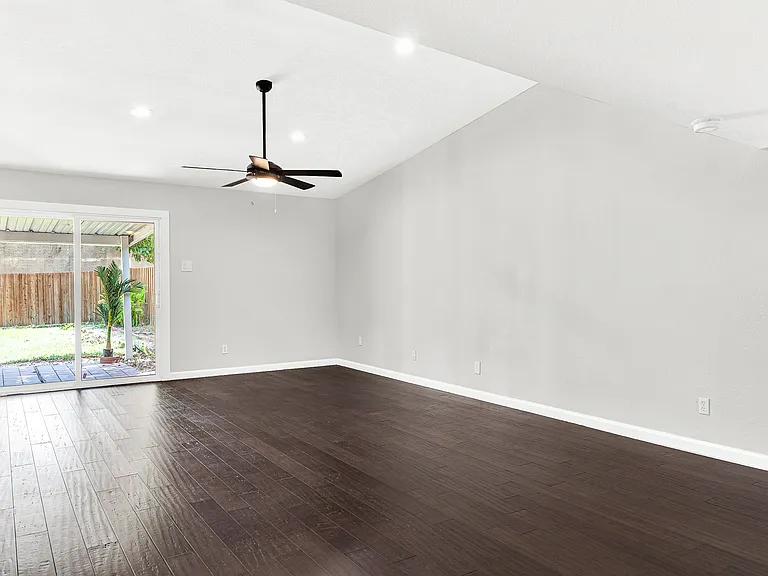 Large living room with high ceilings, engineered wood floors and access to the backyard.