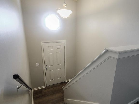View of entrance foyer. Satin nickel entrance light, white trim, vinyl plank flooring in entrance.