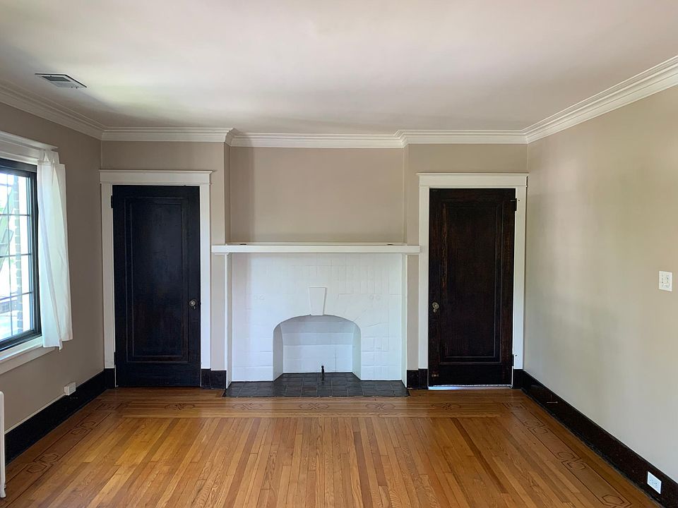 Living room with coat closet to left and front entrance to right. Charming decorative fire place, lots of natural light facing Highland Ave.