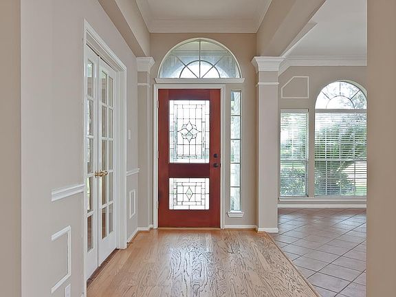 The inviting foyer includes wood floors, high ceilings, arched columns with crown, picture frame and chair rail moulding, recessed lighting and a beautiful wood stained and beveled glass front door.