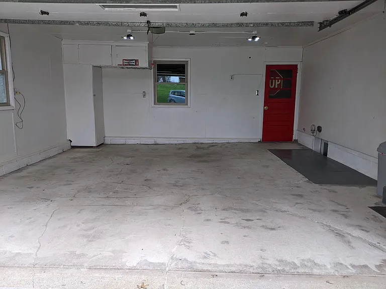 Upper 20 X 20 sq. ft. garage and the entrance to kitchen. The(Red Door) is the entrance to the side garage and the walk up storage area. The window views the lower garage.