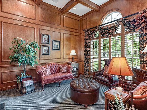 Warm and cozy library with 12' box beam ceiling, rich wood paneling, detail molding and large windows overlooking the front yard