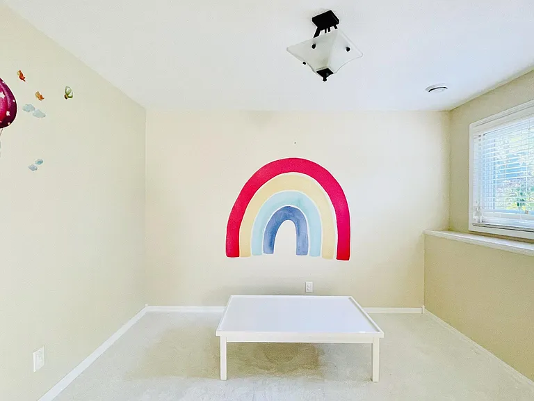 Basement Entertaining Area. Left side view standing at the end of the hallway. Backyard garden view with pink flowers right blooming out of the window. Window faces southwest and receives afternoon sunlight.