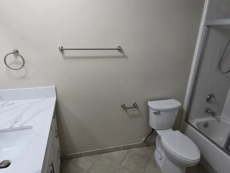 Bathroom has new toilet and new TP holder and towel ring/rods. Bathtub includes glass shower door