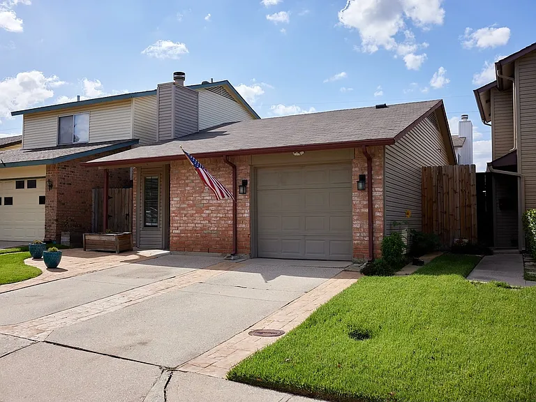 View of front of house with brick siding, a garage, driveway, a chimney, and a shingled roof