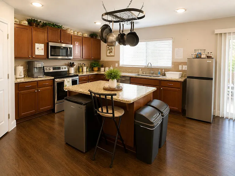 Open kitchen with granite countertops, center island, ample cabinetry, and stainless appliances including fridge and microwav