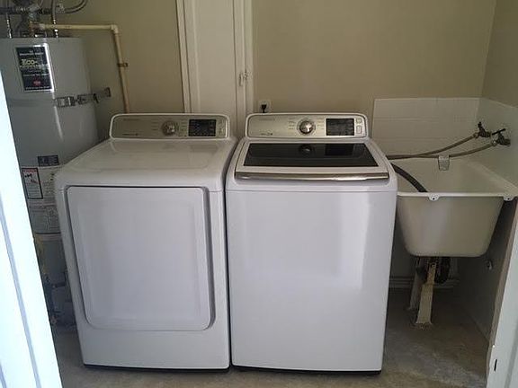 Full size washer and dryer mud room/laundry room with sink. This room has storage and a door to the backyard