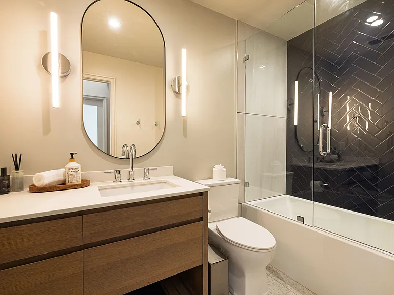 Bathroom 1 has a tub/shower combo with glass doors. There is a cabinet sink with oval mirror.