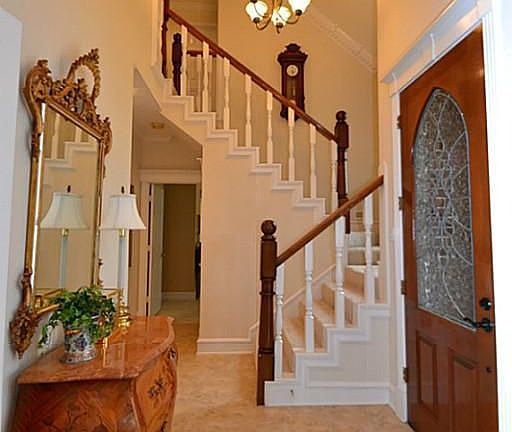 Entry offering a beveled glass front door, tile flooring, two story high ceilings, double crown molding and access to a half bath.