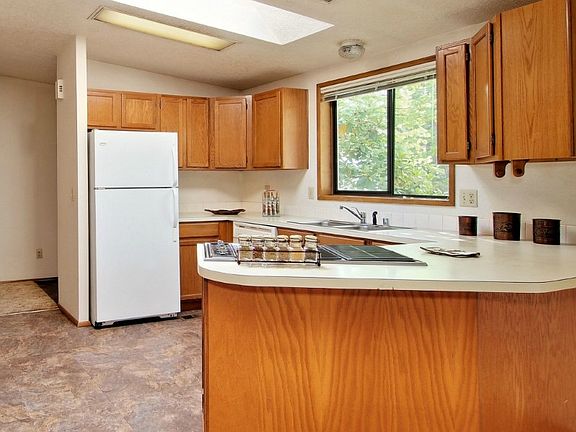 Sunny kitchen with vaulted ceilings, two large skylights and a cooktop on peninsula open to family room, ideal for entertaining.