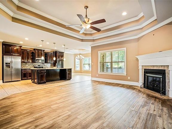 Unfurnished living room with light hardwood / wood-style flooring, a tray ceiling, a tile fireplace, and crown molding