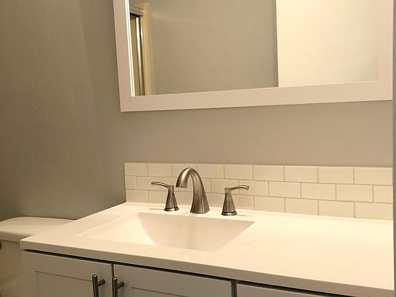 Newly renovated bathroom sink, vanity, mirror, and toilet .