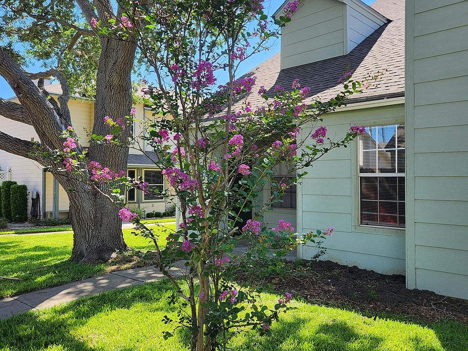 Townhome is shaded by large oak tree and common area landscaping.