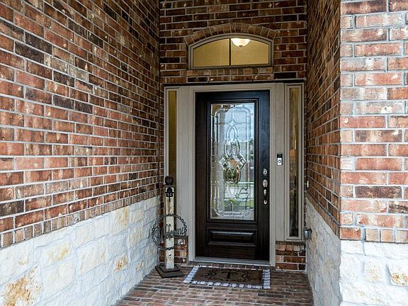 Walk up the curved walkway, passed the landscape and foliage onto this covered front porch!