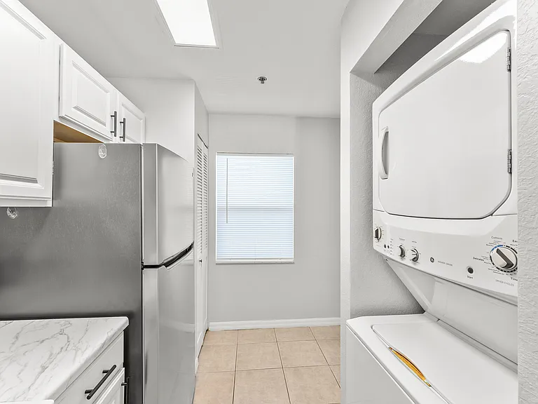Bright modern kitchen featuring sleek stainless steel appliances, elegant white cabinetry, and in-unit washer-dryer. Perfect for efficient living.