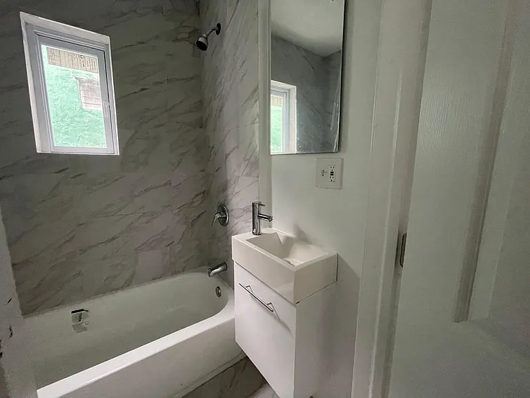 bathroom with tub and granite style tiling