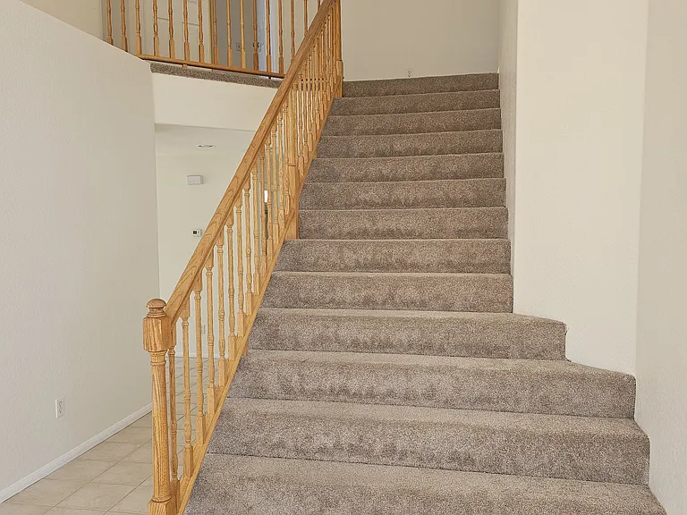 Ascend to the next level on this staircase, featuring wood balusters and plush carpeting.