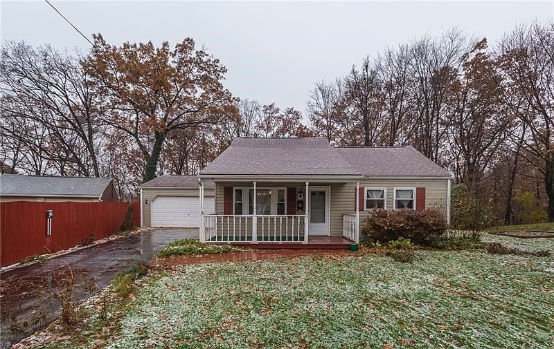 Front of home features a large tabletop yard and blacktop driveway ending at the 2 car attached garage