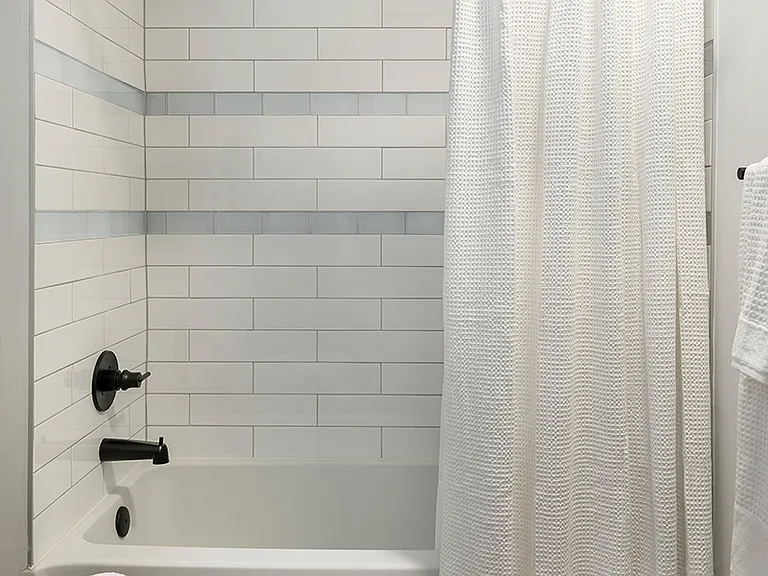 Apartment bathroom with soaking tub and wood-style flooring.