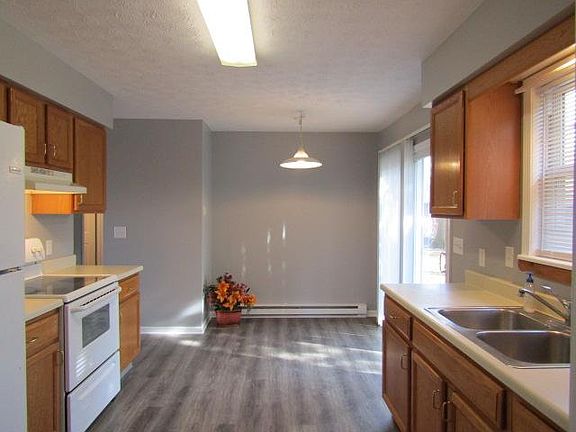 View of kitchen and dinette, light grey walls and brow/gray laminate flooring. Electric range and refrigerator provided.
