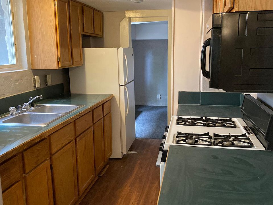 Kitchen area is adjacent to living space with generous countertop space, gas range, microwave and open shelf storage pantry.