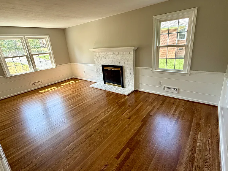Large family room with painted wainscotting, hardwood floors and a gas log fireplace.