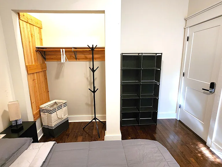 Bedroom with hardwood floors, a closet with built-in shelf and hanging rod, plus convenient storage near the entry.